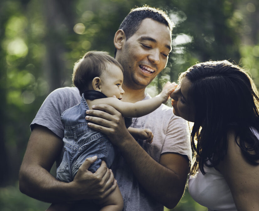 Man holding baby while the baby is touching a woman's face.